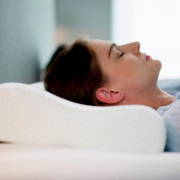 Mujer tumbada en una cama con una almohada cervical
