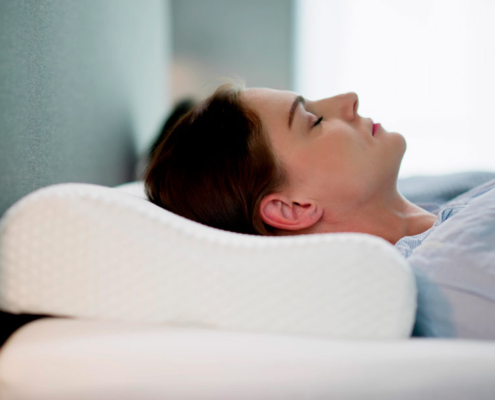Mujer tumbada en una cama con una almohada cervical
