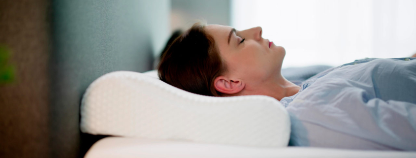 Mujer tumbada en una cama con una almohada cervical