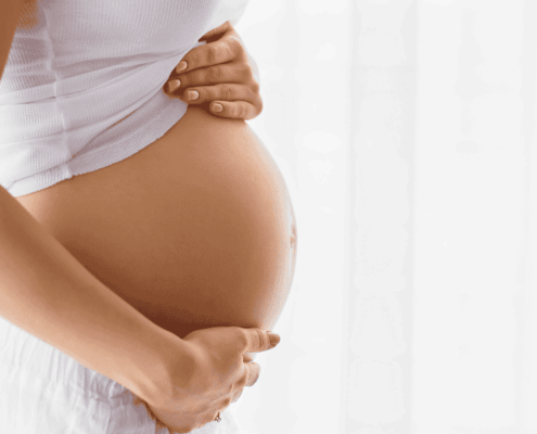 Mujer embarazada acariciando su vientre, una imagen que representa el significado de soñar que estás embarazada y la importancia de un buen descanso con colchón de muelles ensacados