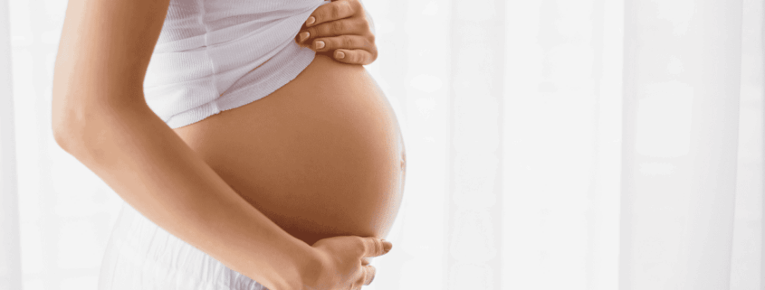 Mujer embarazada acariciando su vientre, una imagen que representa el significado de soñar que estás embarazada y la importancia de un buen descanso con colchón de muelles ensacados